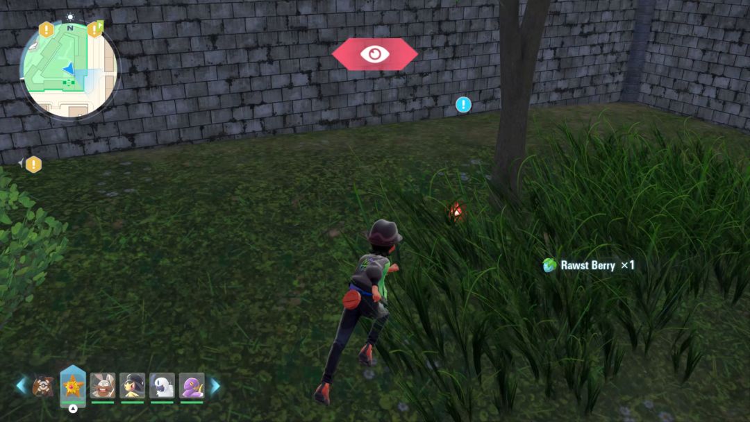 Near a tree, lying in some grass with rock walls forming a corner behind it, lies the Revitalizing Twig.